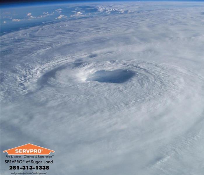 Top view of hurricane with the eye wall near the center.  SERVPRO of Sugar Land logo & information in the bottom left corner