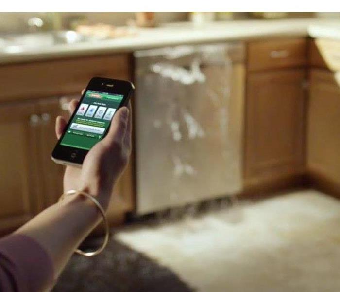 SERVPRO app on phone in front of overflowing dish washer
